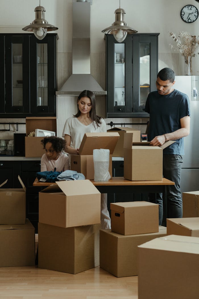 journey Family unpacking boxes together in a modern kitchen after moving into a new home.