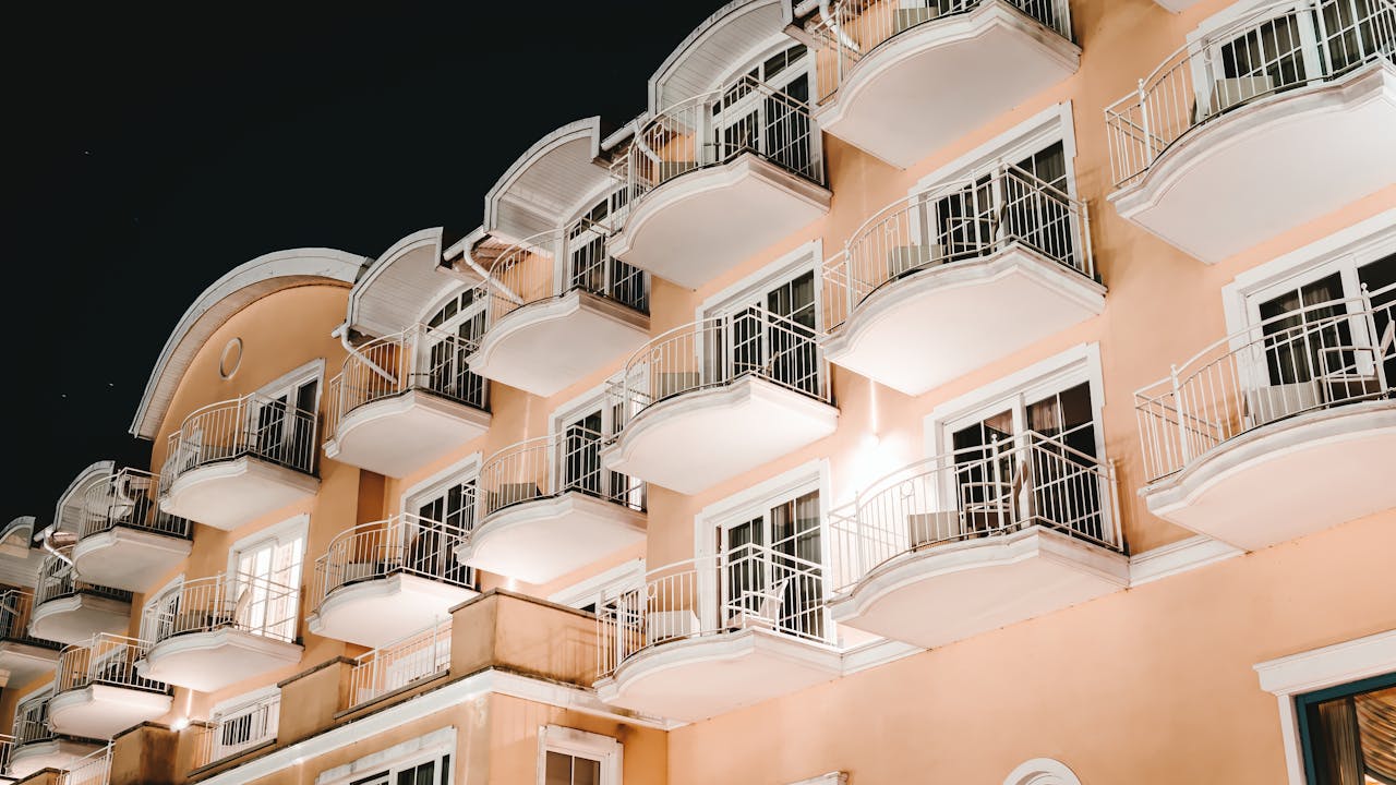 services-01 Low angle view of a modern building with balconies lit at night, showcasing architectural elegance.